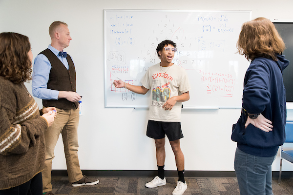 Teacher advising students on lesson.