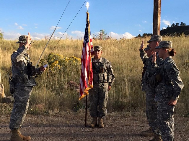 Army ROTC group outside in full gear next to the American flag.
