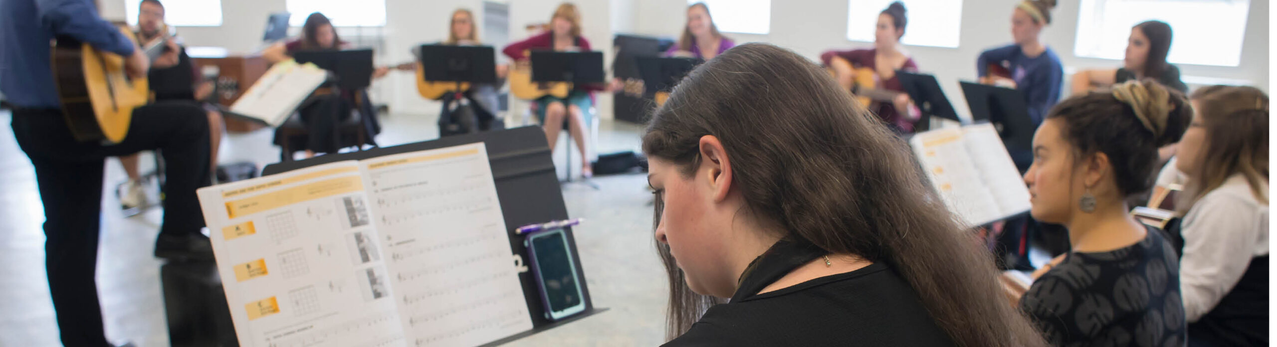 Students learning guitar in the classroom.