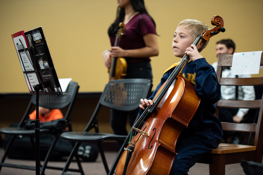 Kid playing a cello in the UNC String Project.