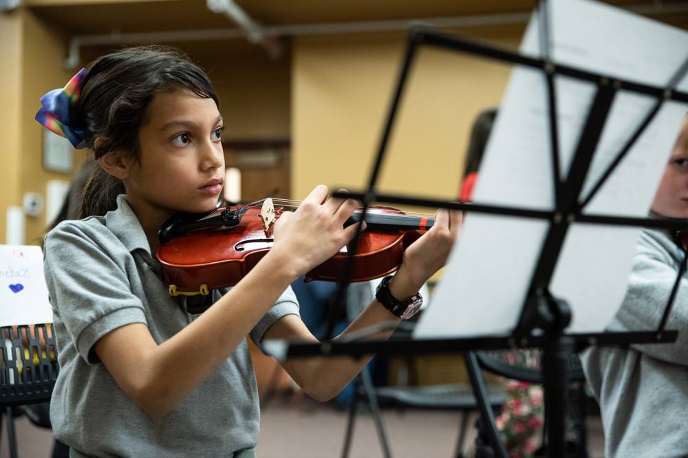 Kid plating a violin in the UNC String Project.