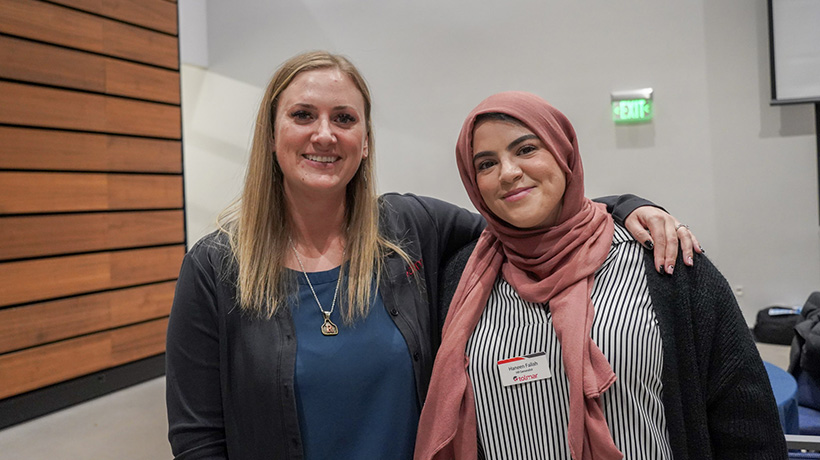 Two women smiling and standing close together, one with her arm around the other, representing Tolmar at an event.