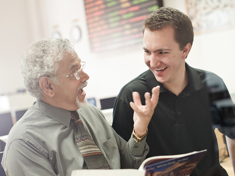 Professor Vish Iyer with a a male student laughing and learning