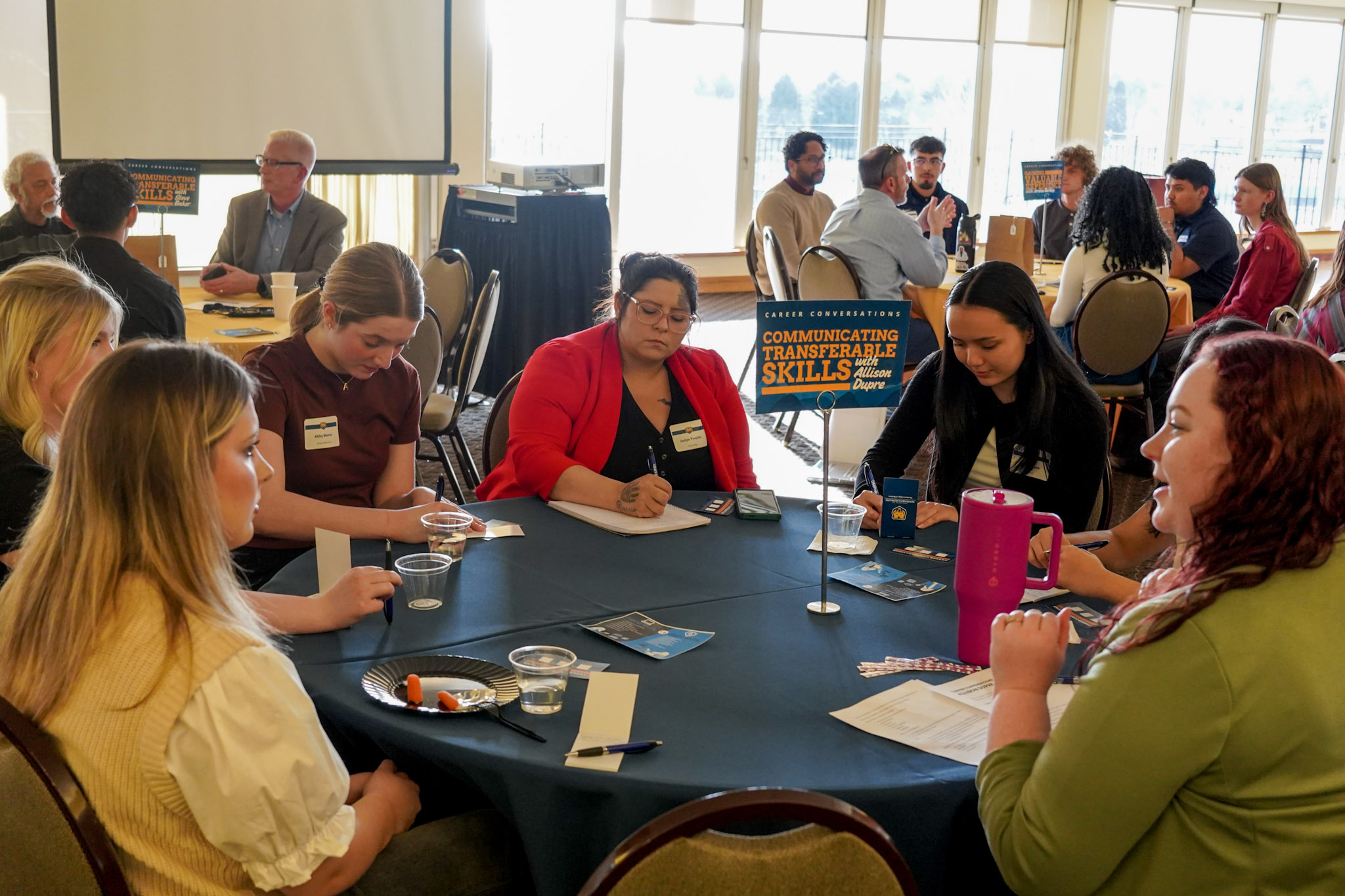 A group of students participating in a career conversation event, sitting around a table with a sign that reads 