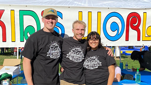 Two students and a female student smiling together with a vibrant, colorful background.