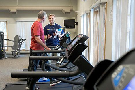A UNC trainer talking to a patient on the treadmill.