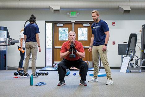 UNC trainers guiding clients in the gym.
