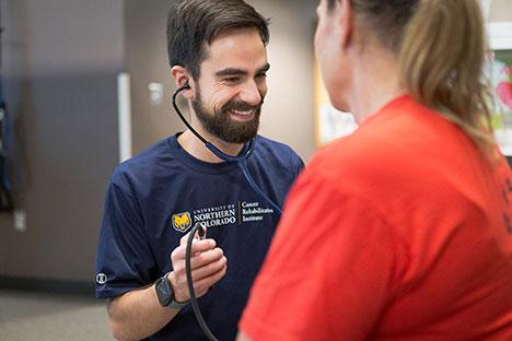 A UNC trainer checking a client's heart rate.