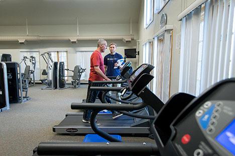 A UNC trainer talking to a client on the treadmill.