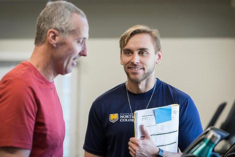 A UNC trainer talking to a client on the treadmill.