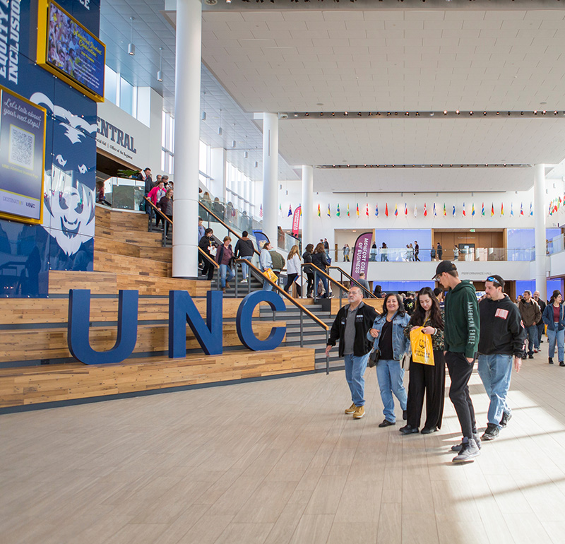 Students walking through the spacious interior of the UNC building, with large blue 