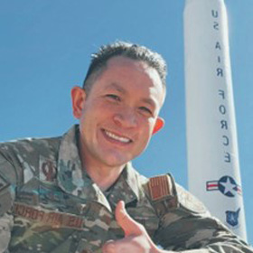 Captain Robert Butler posing next to a pillar with the words "US AIR FORCE"