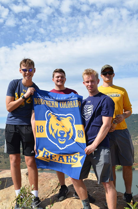 A group of cadets holding up a flag of UNCO.