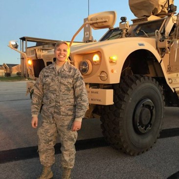 Techincal Sergeant Meghan Kalisek standing outside next to a military vehicle.