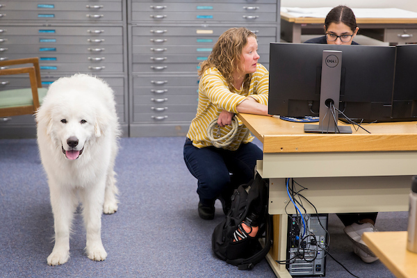 Jessica Salo helping one of her students, her dog is to the side of her.