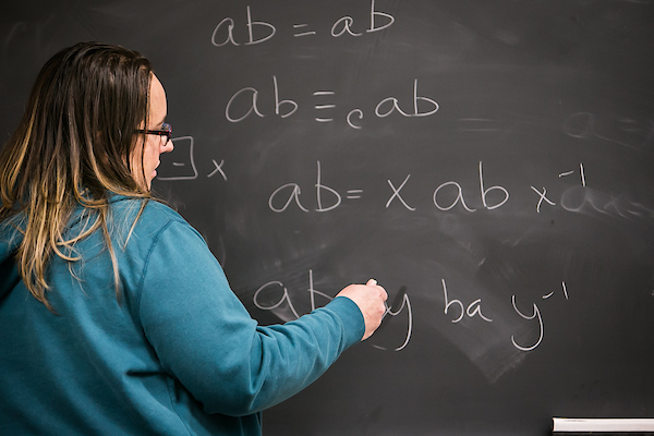 Student teacher writing on chalkboard.