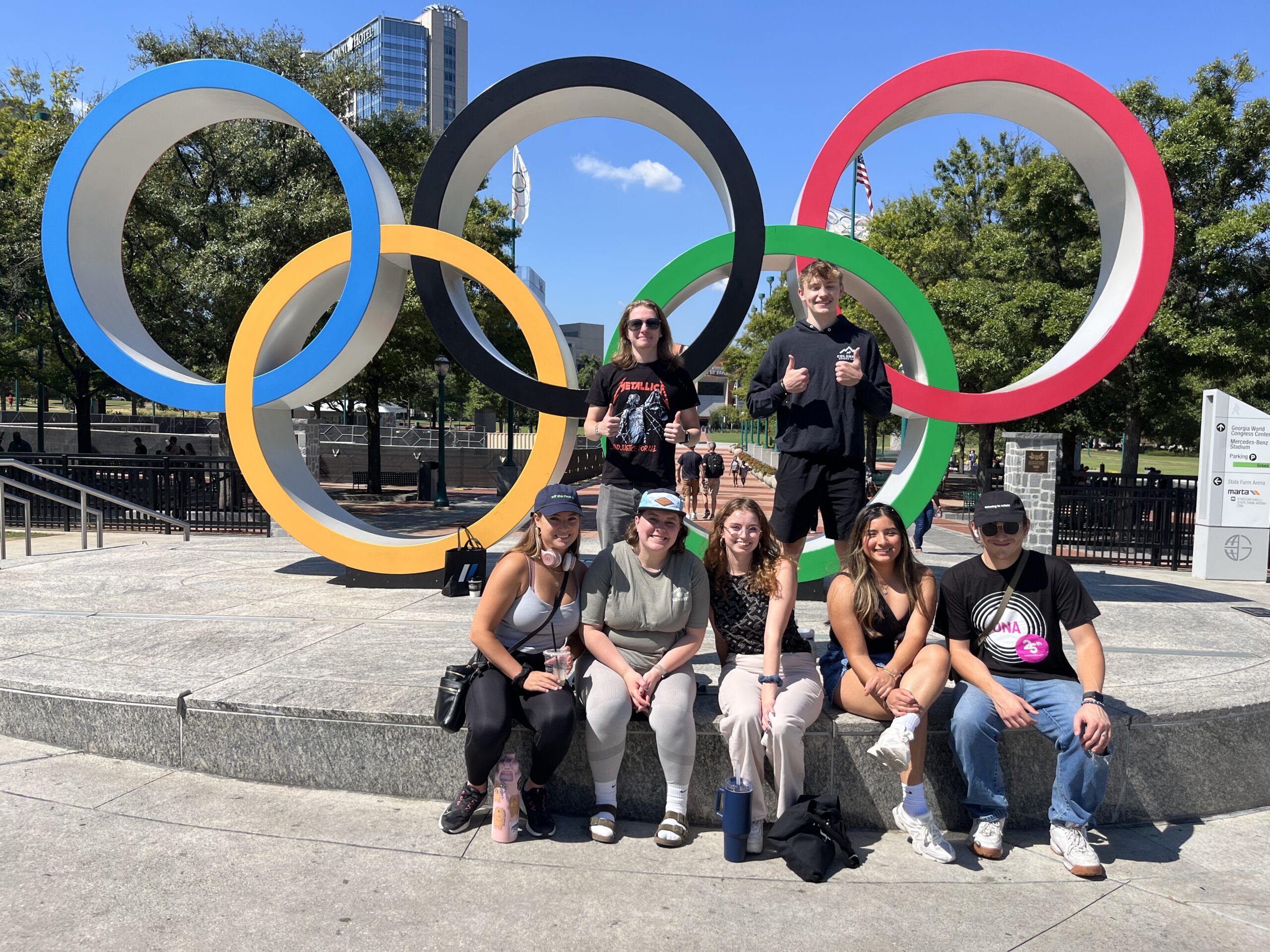 7 students in front of the Olympics statue (Blue, gold, black, green, and red Circles)