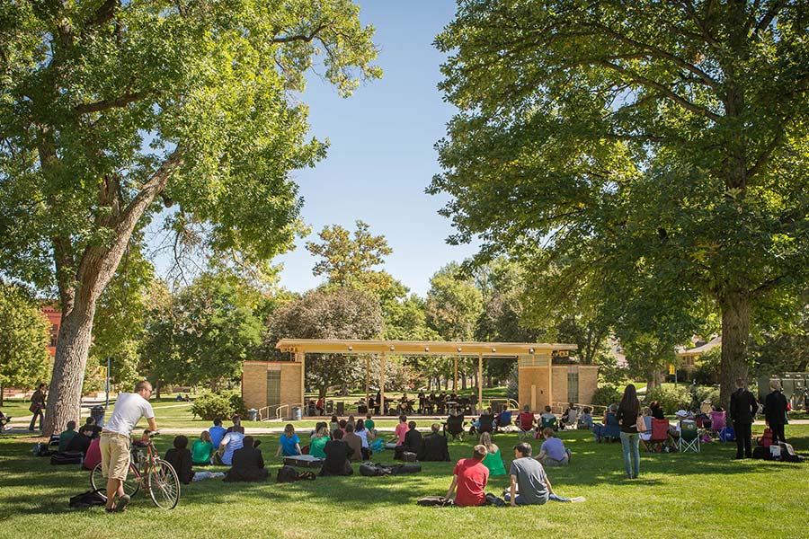 Students lounge on the lawn in front of the Garden Theater while a band plays music on stage.