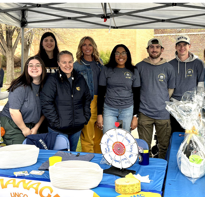 Members of the Event Management Club, wearing matching t-shirts, smiling and standing together at an even