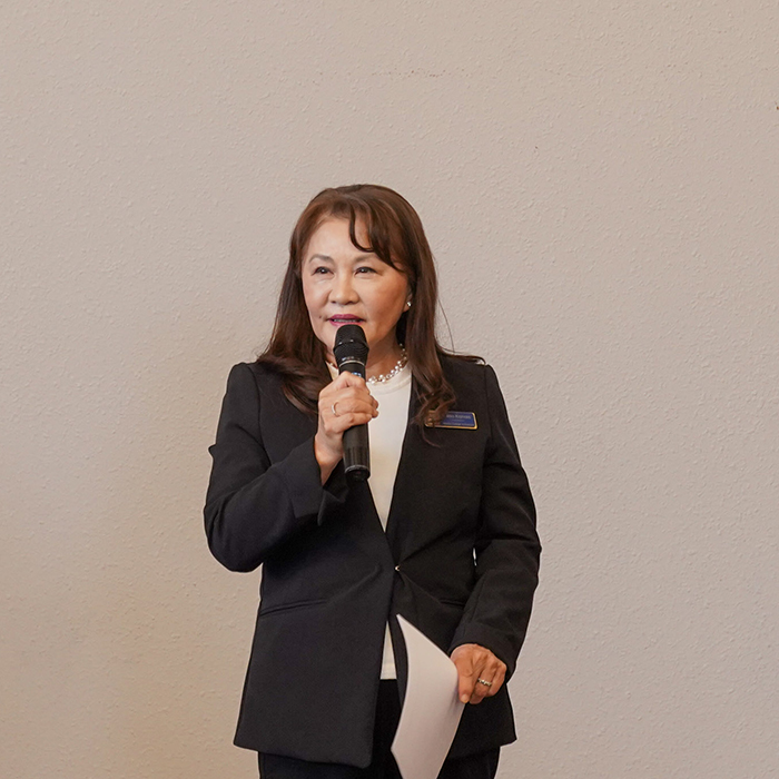 Professor Keiko Krahnke, holding a microphone, wearing a black suit jacket and a white t-shirt. Presenting at Innovation Talks 20205