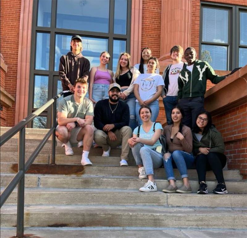 Marketing Club students smiling and sitting together in front of Kepner Hall for a group photo
