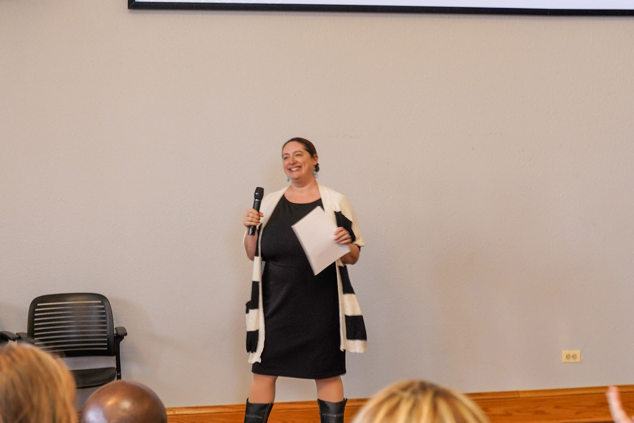 Julie Pink speaking at Innovation Talks, holding a microphone and gesturing with her hand, while addressing an audience focused on her presentation.