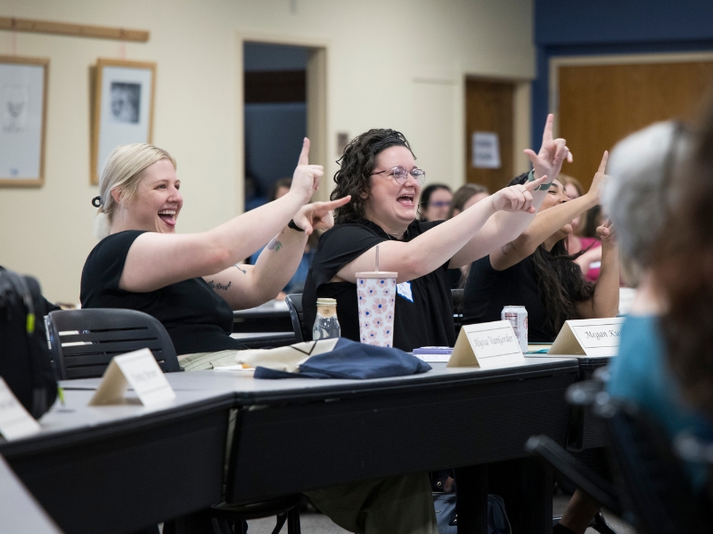 a group of students in class are signing back to their instructor with what they've just learned in the american sign language and interpreting studies class