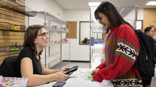 A student volunteer helps another student check out.