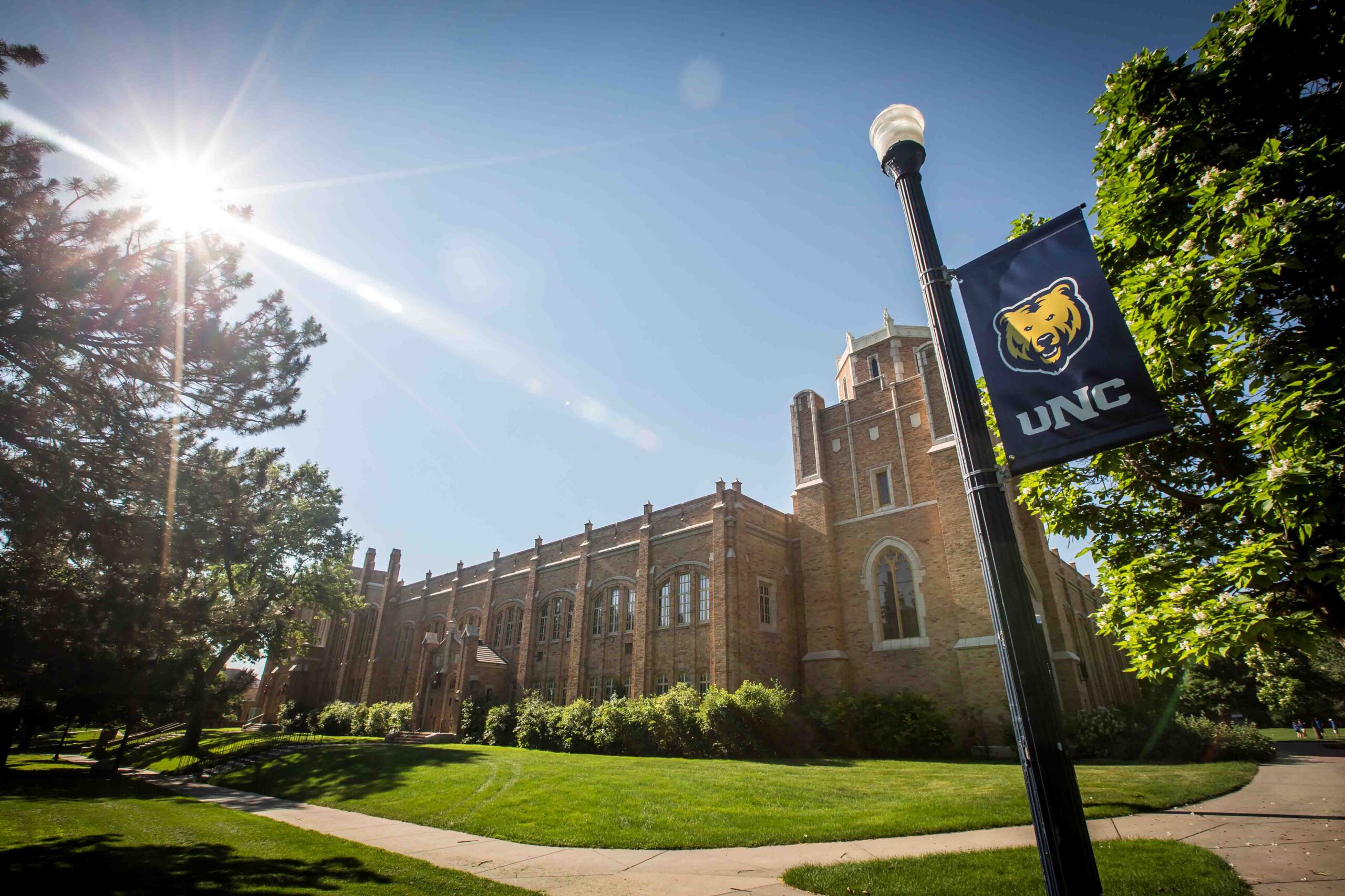 The exterior of Gunter Hall with a lightpole holding a UNC Banner in the foreground.