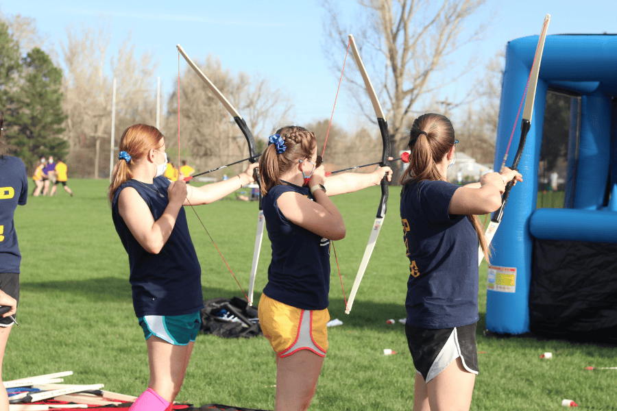 3 people in a line shooting bow and arrows