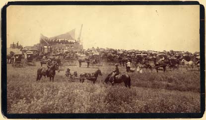 A preserved image from the late 1800s depicting several people crossing a clearing on horseback and in carriages.