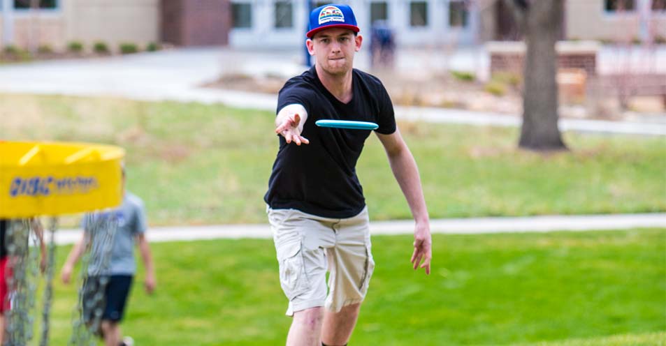 A student playing disc golf.