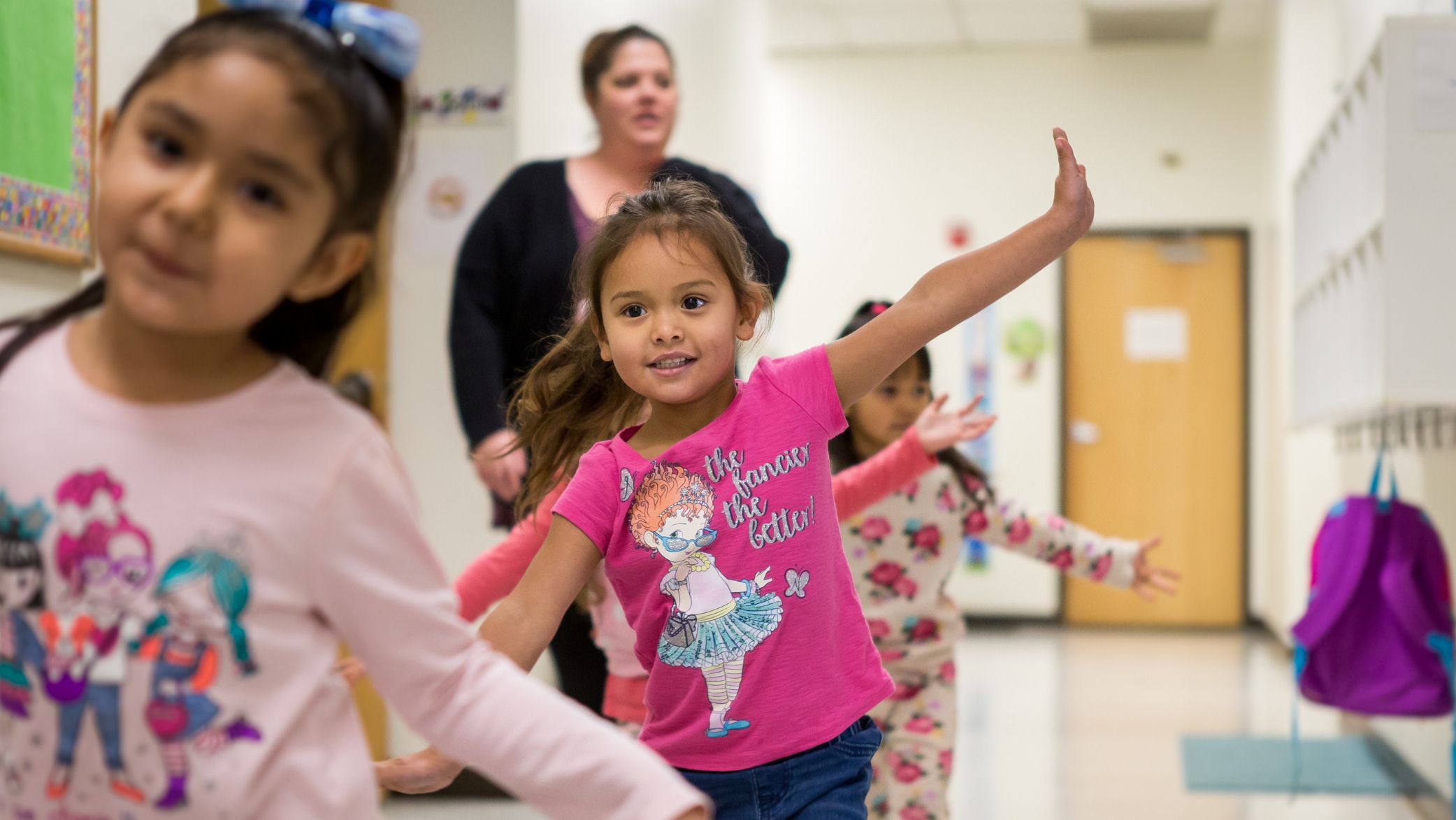 An early childhood education class is in line having fun in the hallway