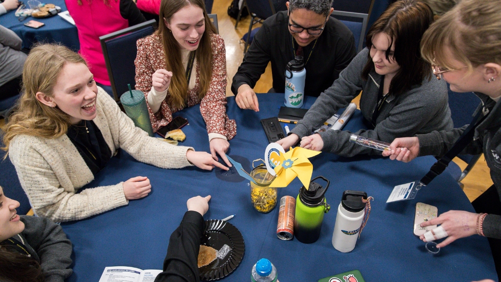A group of five students are shown huddle up working closely together to collaborate in one of the workshop sessions during the Future Teacher Conference