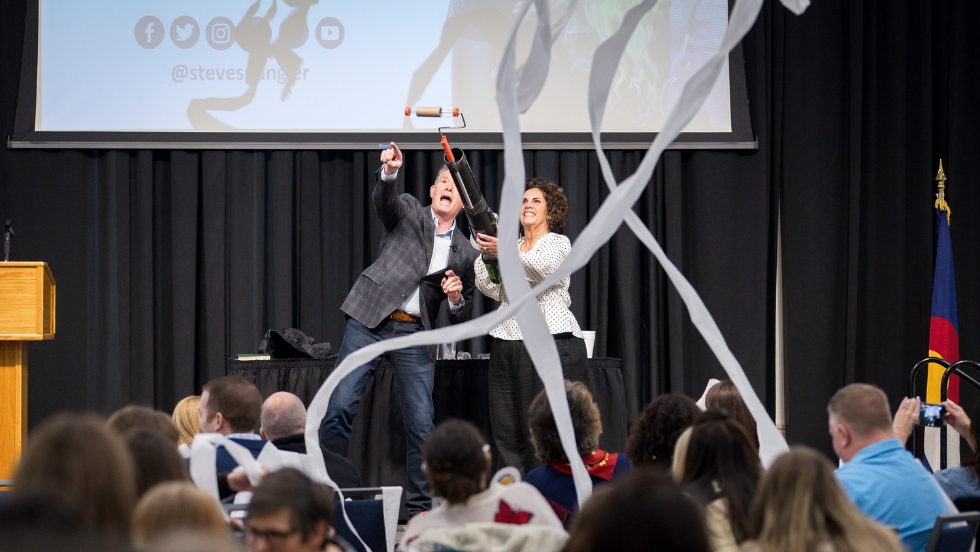 Steve Spangler and Suzette Youngs are shooting out toilet paper confetti from a handheld cannon for the Future Teacher Conference to hype up the students in attendance
