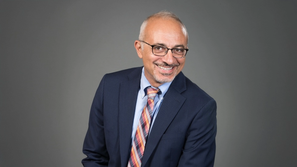 Headshot of Dean Kamel Haddad in a business suit with grey background