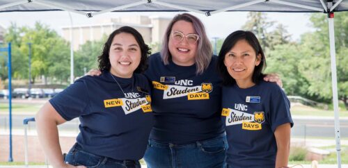 Three UNC faculty work at a booth during the New Student Days event.