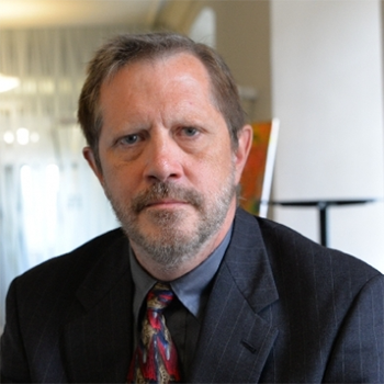 a older man, wearing a dark suit, smiling