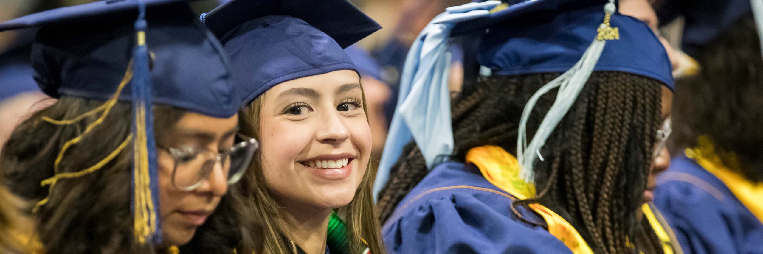 Smiling graduate waits for her name to b called during commencement.