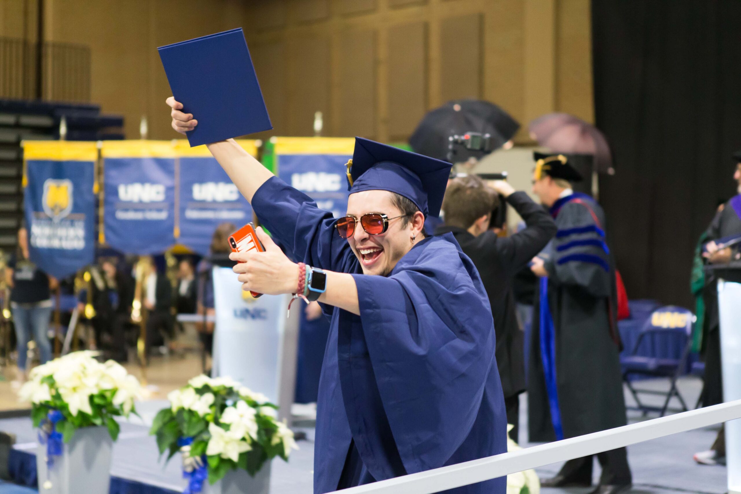Graduate takes a selfie with his diploma at commencement.