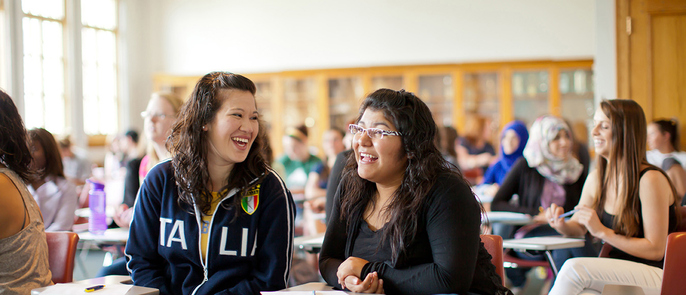 Two students laugh together in a classroom.