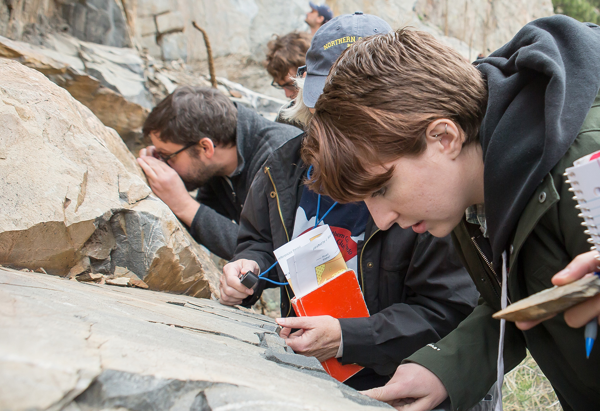 UNC students study age lines on a boulder.