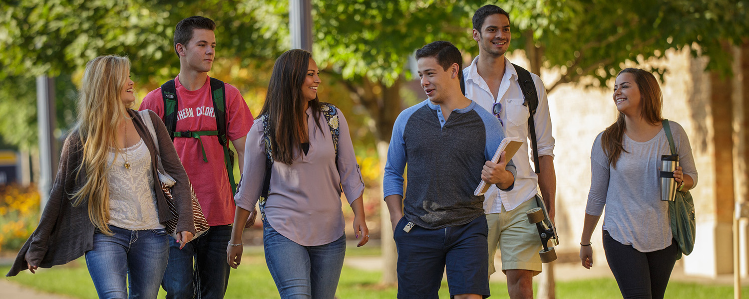 Students walking and talking together on a campus sidewalk.