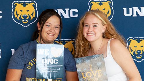 Two female students smiling and holding 