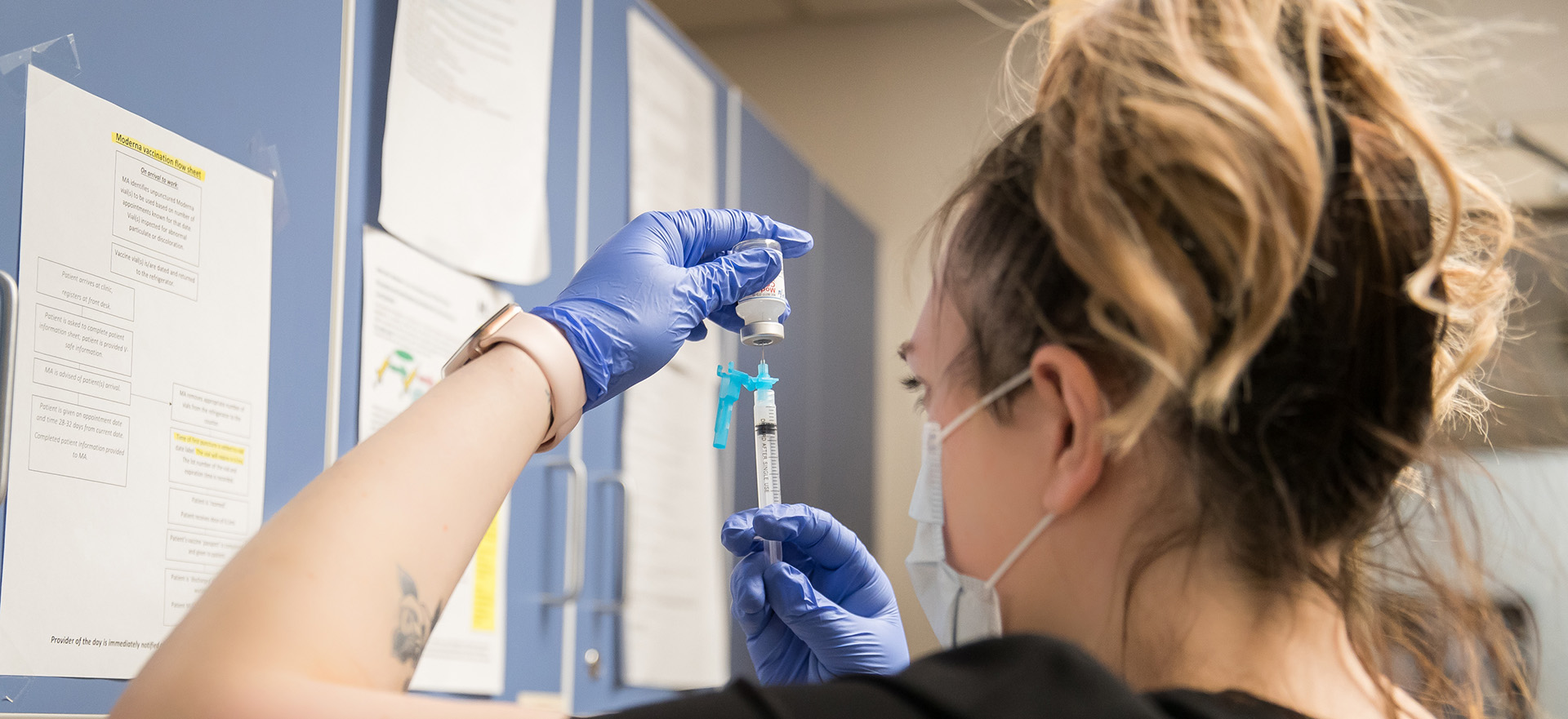 A UNC student injects a syringe into a bottle of medicine to withdraw the medication.