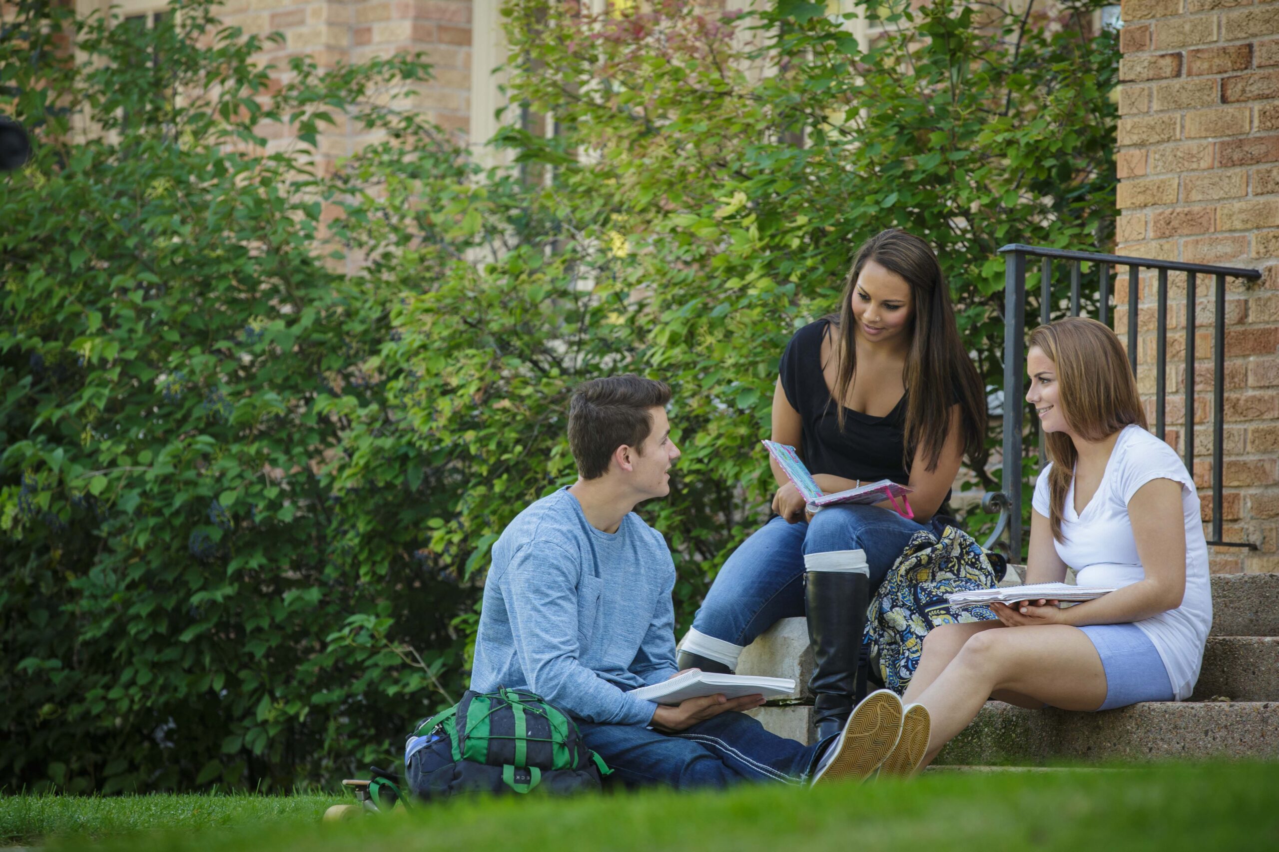 Three students sitting outside reading notes together