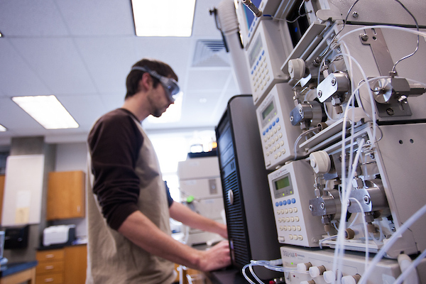Student operating computer and machinery in chemistry lab