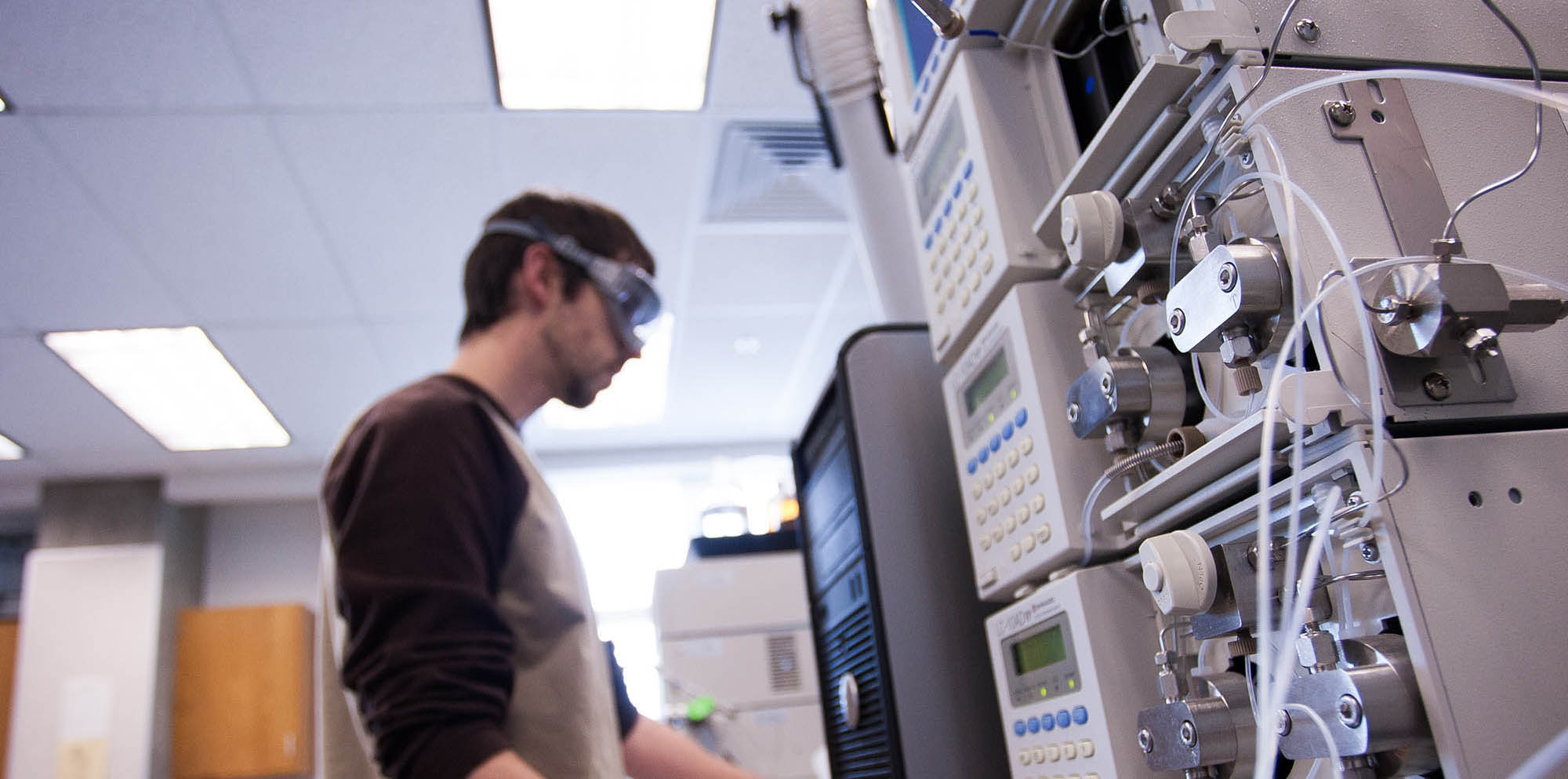 A student out of focus stands in from of an indescript machine.