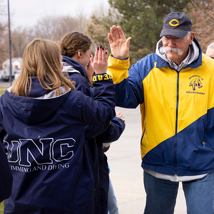 Alum Joe Drew high fiving a swimming and diving athlete at the 2025 women's walk.