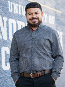 Fernando Beltran standing next to a painted University of Northern Colorado logo.
